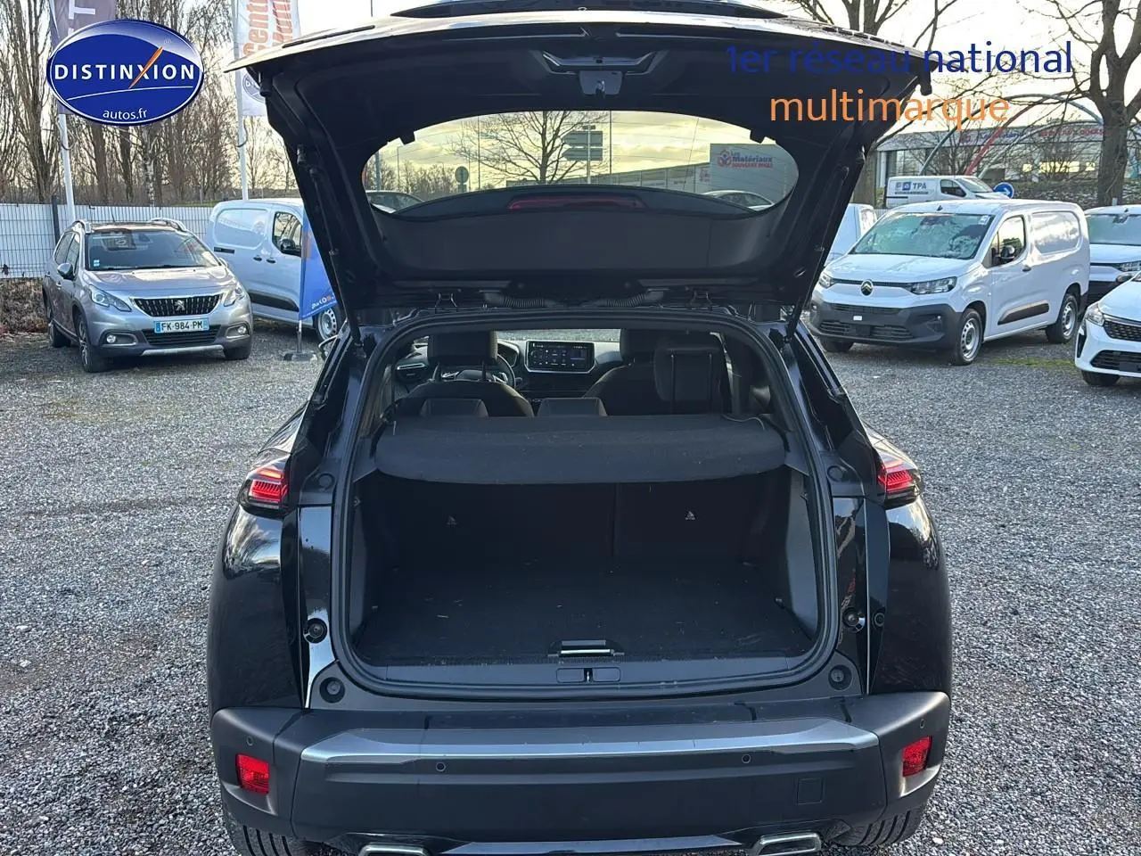 Vue arrière d'une Peugeot 2008 noire 2025 avec coffre ouvert, feux arrière LED et sortie d'échappement chromée visible.