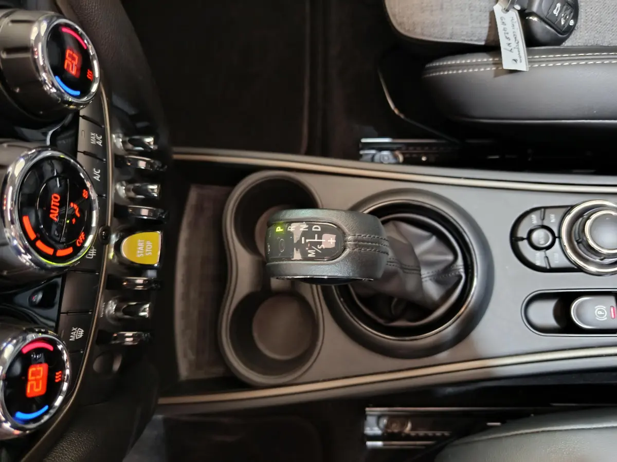 Vue rapprochée de la console centrale du MINI Countryman blanc, mettant en valeur le levier de vitesse automatique et les commandes climatisation.