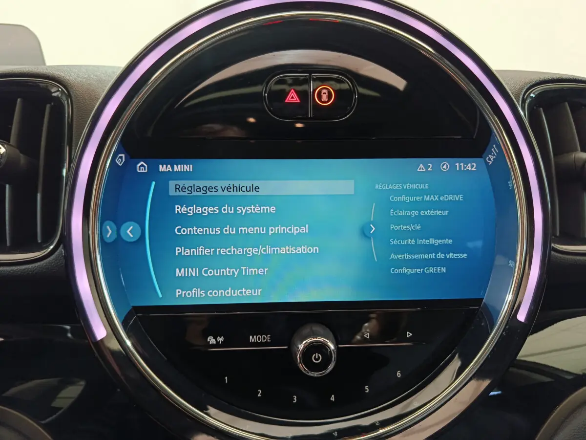 Gros plan sur l'écran tactile central rond du tableau de bord du MINI Countryman blanc, affichant les réglages du véhicule.