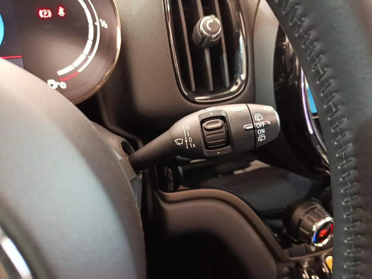 Gros plan sur la commande d’essuie-glace à gauche du volant cuir dans l’habitacle du MINI Countryman blanc.