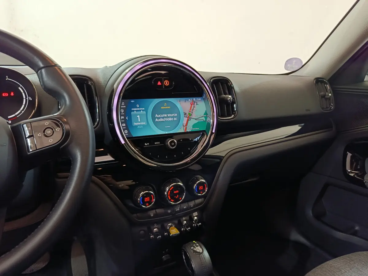 Vue intérieure côté conducteur du tableau de bord noir du MINI Countryman avec écran tactile circulaire et commandes digitales.