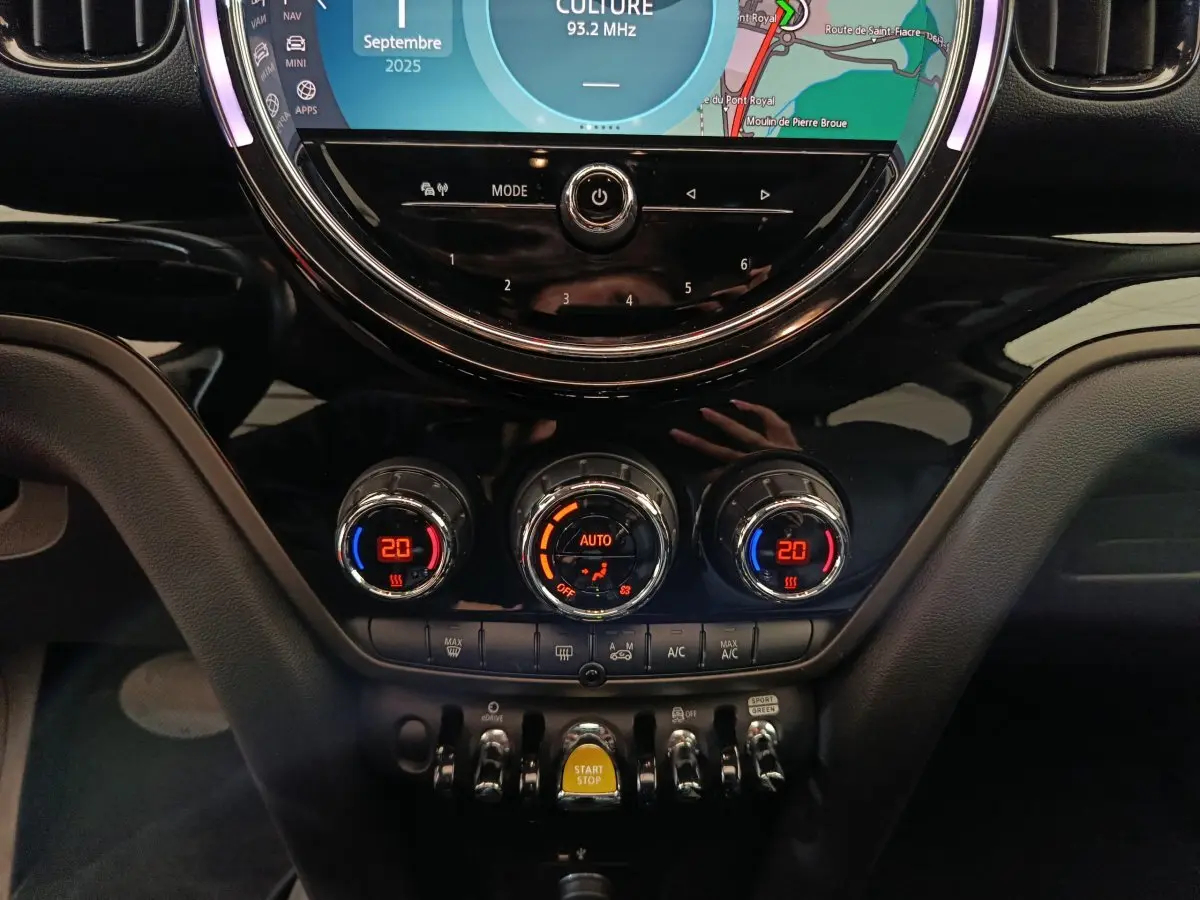 Gros plan sur la console centrale du MINI Countryman blanc, mettant en valeur les commandes de climatisation et l’écran tactile rond.