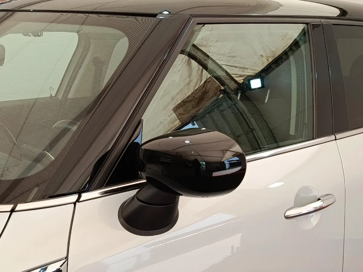 Gros plan sur le rétroviseur noir côté gauche et la porte blanche d’une MINI Countryman hybride rechargeable 2021.