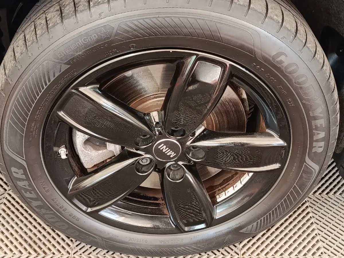 Gros plan sur la jante noire brillante et le pneu Goodyear d’un MINI Countryman blanc, vue latérale.