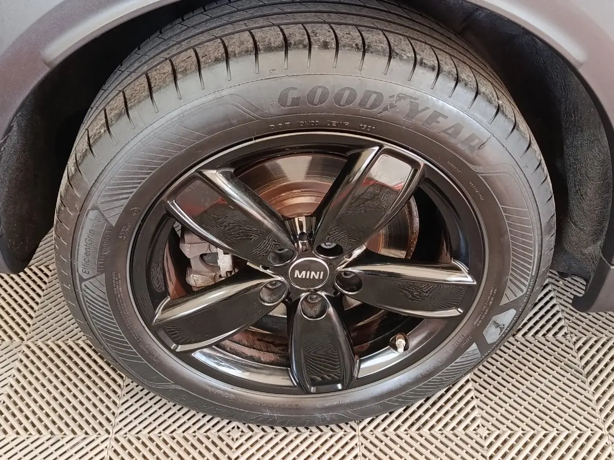 Gros plan sur la roue avant droite noire brillante du MINI Countryman blanc, avec pneu Goodyear visible.