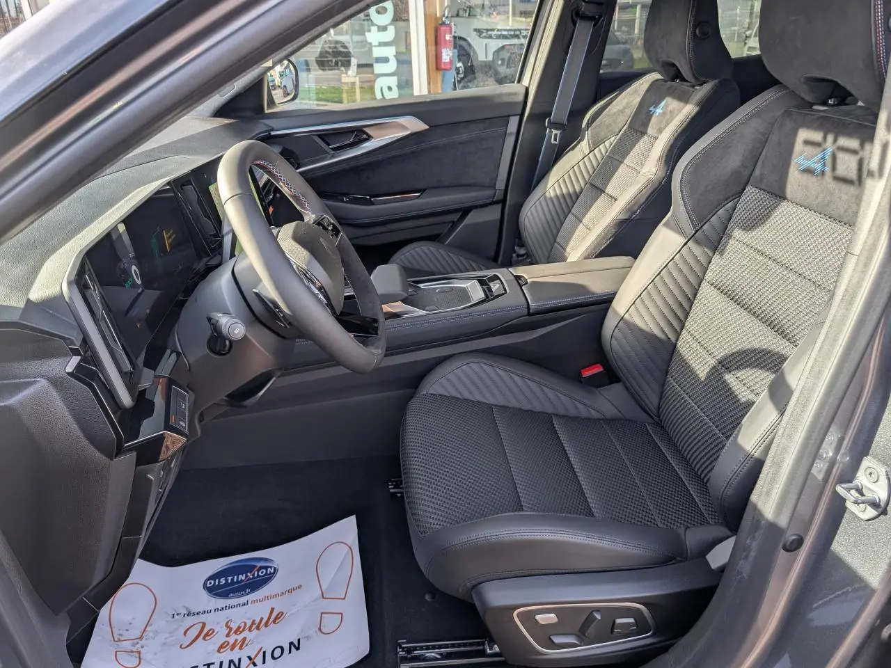 Vue intérieure côté conducteur du Renault Austral gris métallisé, sièges Alcantara avec surpiqûres tricolores et volant textile.