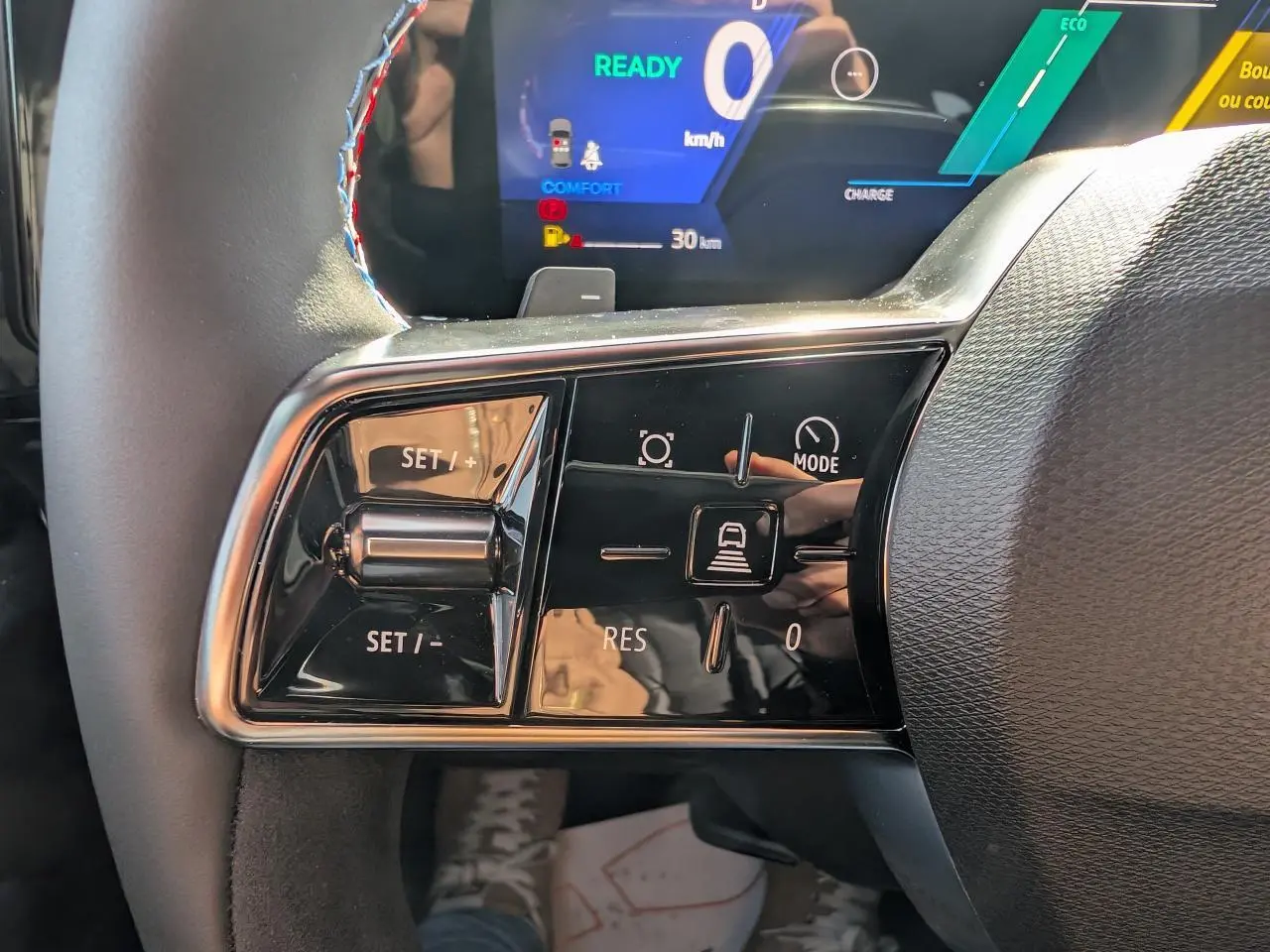 Gros plan sur les commandes au volant côté gauche du Renault Austral gris métallisé, avec affichage numérique en arrière-plan.