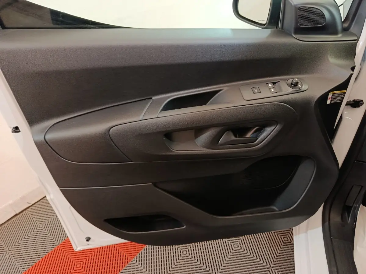 Vue intérieure côté gauche de la porte avant blanche du Peugeot Partner 2025 avec commandes électriques et poignée intégrée.