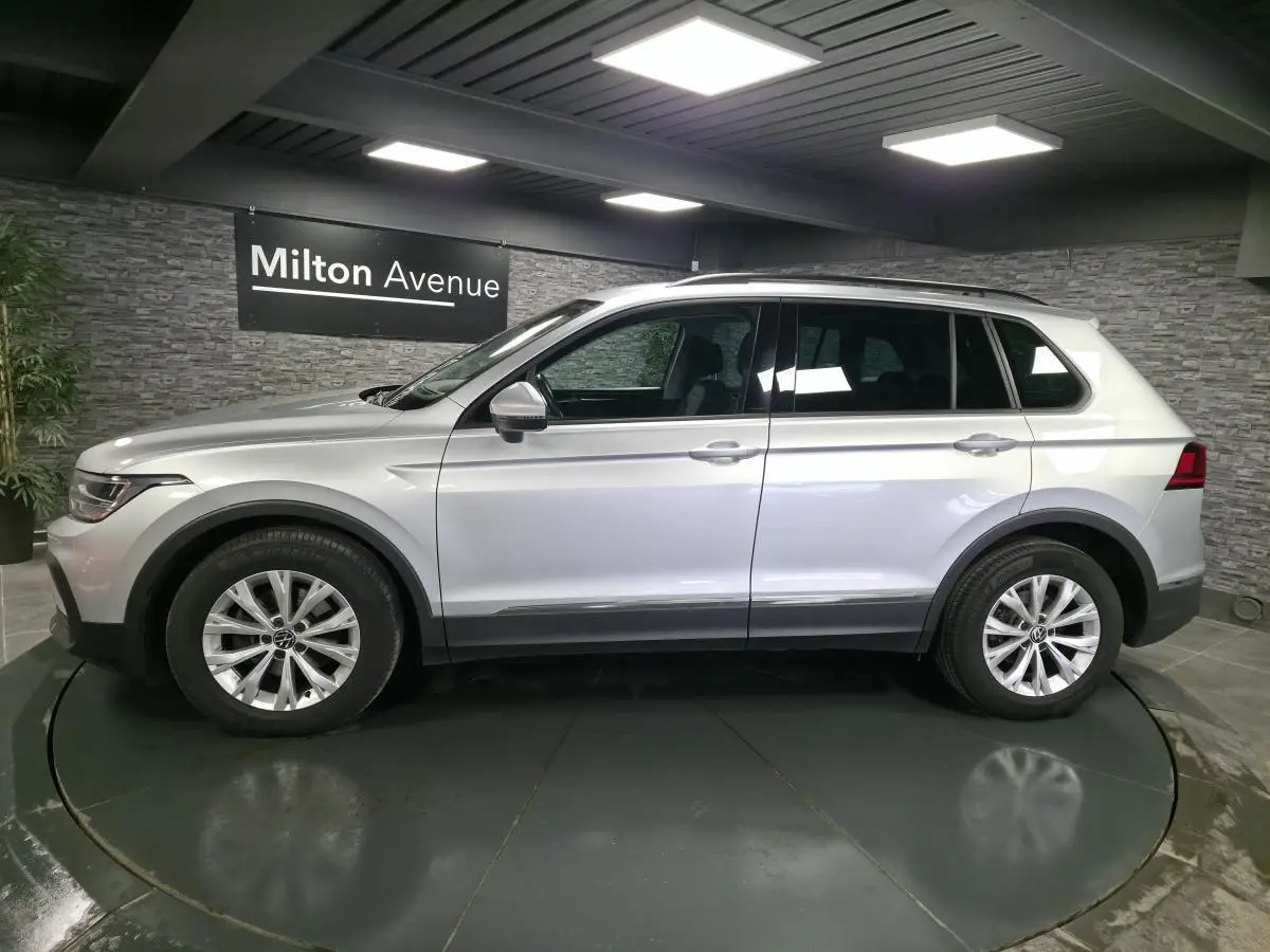 Volkswagen Tiguan gris métallisé vu de profil côté gauche dans un showroom avec jantes alliage 17 pouces.