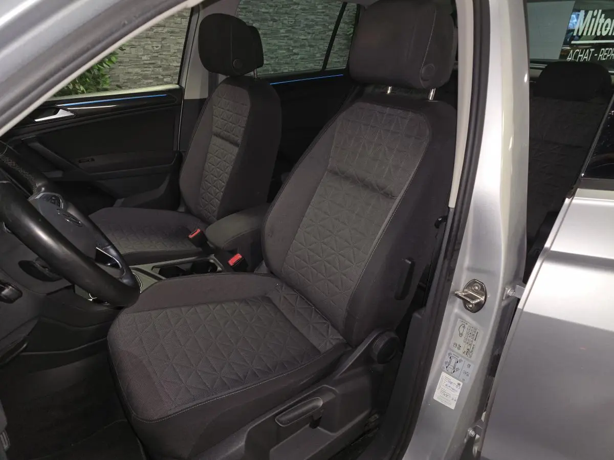 Vue intérieure côté conducteur du Volkswagen Tiguan gris 2023, sièges tissu noir avec motifs géométriques.