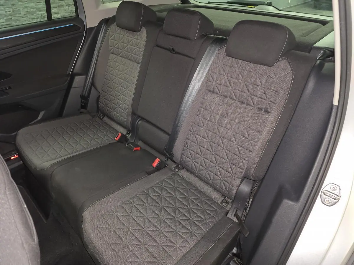 Vue intérieure des sièges arrière en tissu gris à motif géométrique du Volkswagen Tiguan 2023, avec ceinture de sécurité visible.