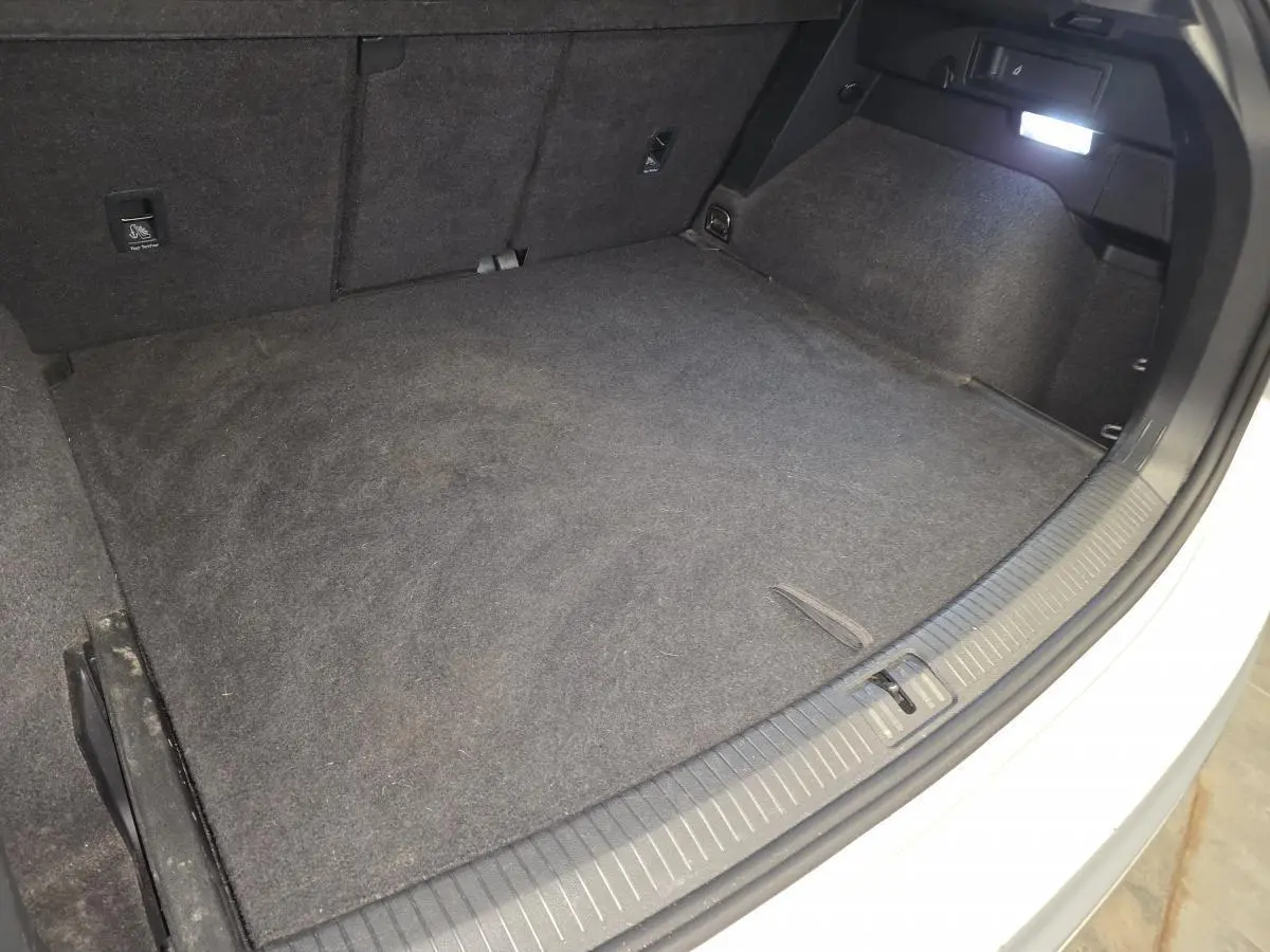Coffre ouvert du Volkswagen Tiguan gris, vue plongeante montrant l'espace de chargement et la moquette intérieure.