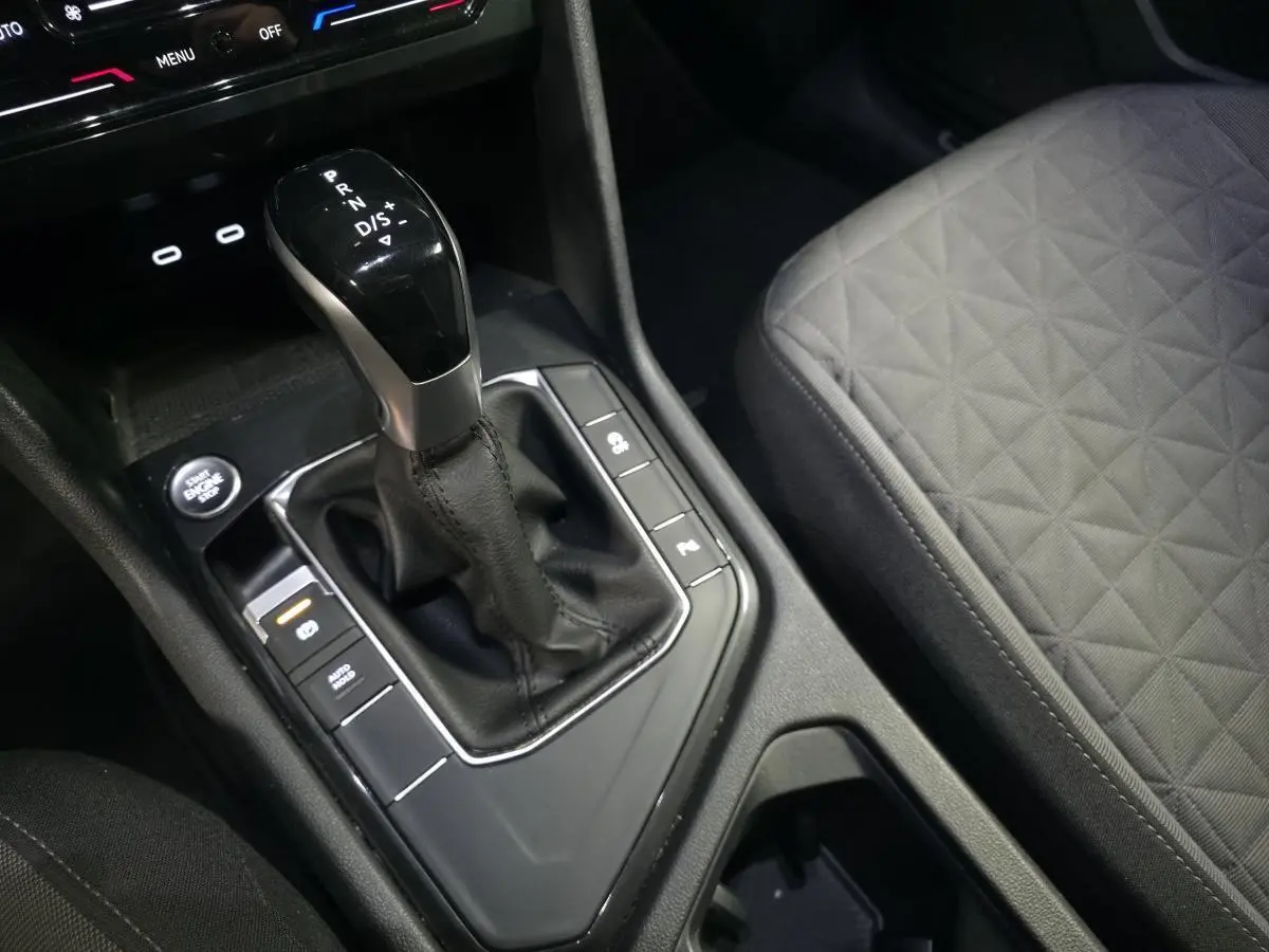 Gros plan sur la console centrale du Volkswagen Tiguan 2023 avec levier de vitesse automatique et sellerie tissu grise.