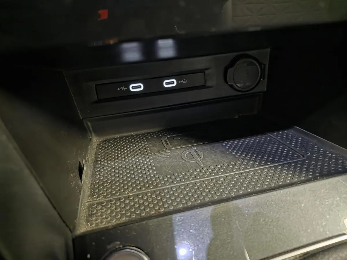 Gros plan sur la console centrale du Volkswagen Tiguan gris 2023, montrant les ports USB-C et la zone de charge sans fil.