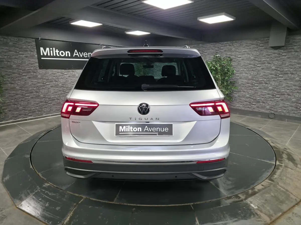 Vue arrière d'un Volkswagen Tiguan gris métallisé 2023 avec feux LED allumés dans un showroom.
