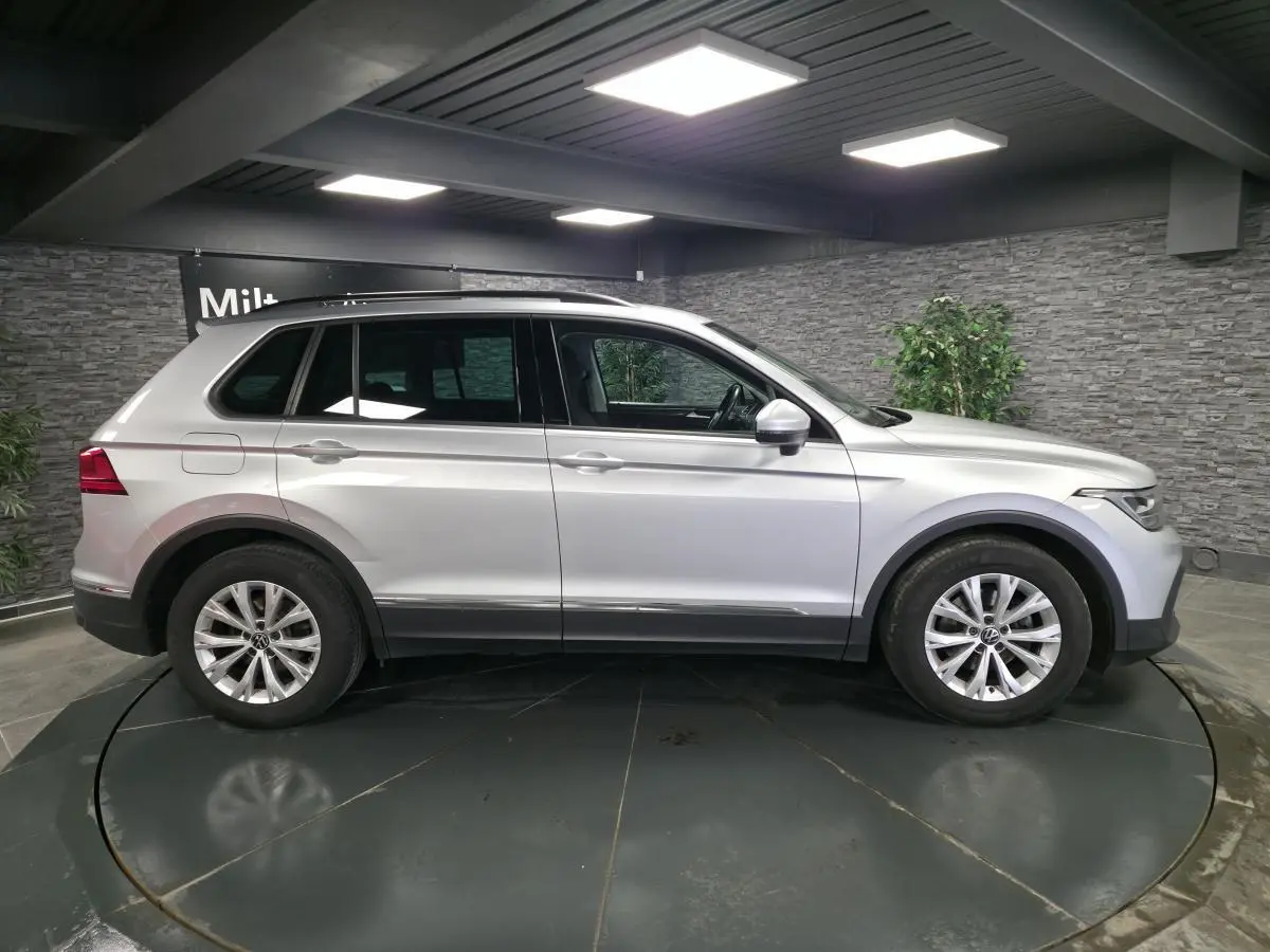 Profil droit d’un Volkswagen Tiguan gris métallisé 2023 en intérieur avec jantes alliage 17 pouces.