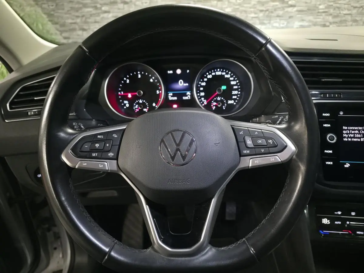 Vue rapprochée du volant cuir noir multifonctions d’un Volkswagen Tiguan 2023 avec tableau de bord et écran tactile visibles.