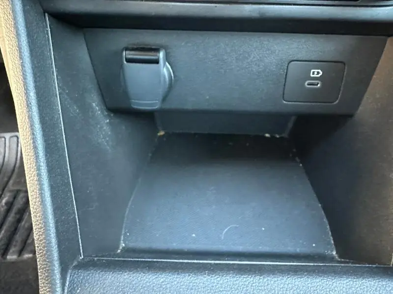 Gros plan sur la console centrale noire du Dacia Jogger 2025 avec prise USB-C et prise 12V visibles.