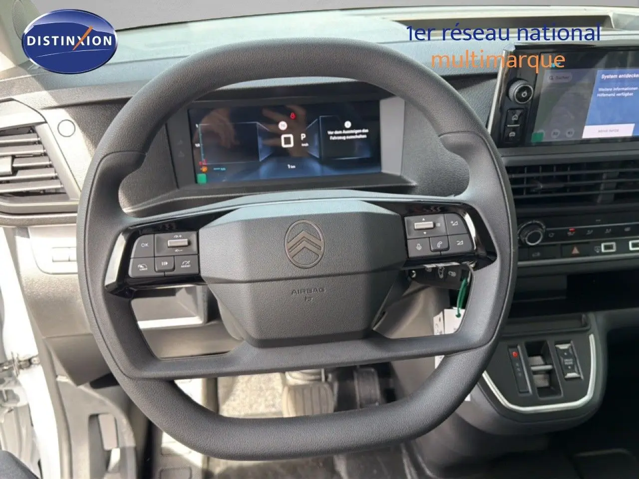 Vue intérieure centrée sur le volant multifonction noir du Citroën Jumpy blanc Kaolin avec tableau de bord digital.