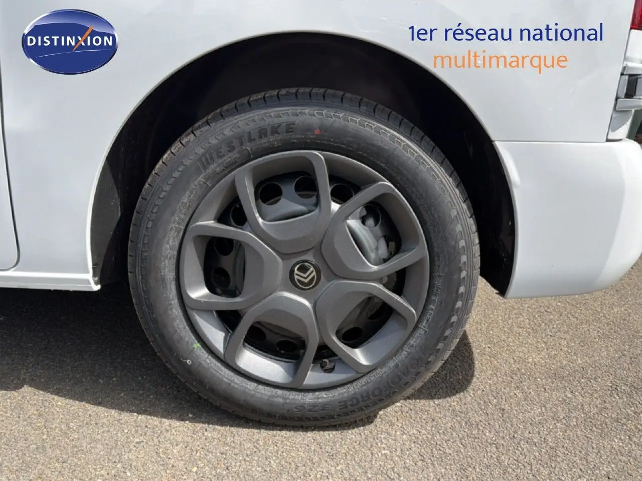 Gros plan sur la roue avant droite d’un Citroën Jumpy blanc Kaolin avec jante grise au design moderne.