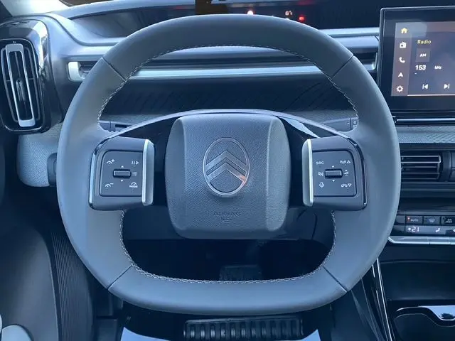 Vue rapprochée du volant en cuir synthétique gris foncé de la Citroën C3 Hybrid 145 E-DCS6 MAX avec commandes intégrées.