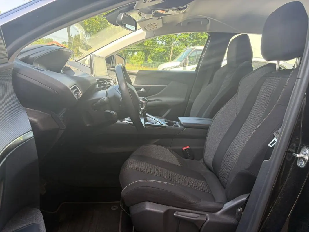 Vue intérieure côté conducteur du Peugeot 3008 noir 2021, montrant les sièges tissu et le tableau de bord avec écran central.