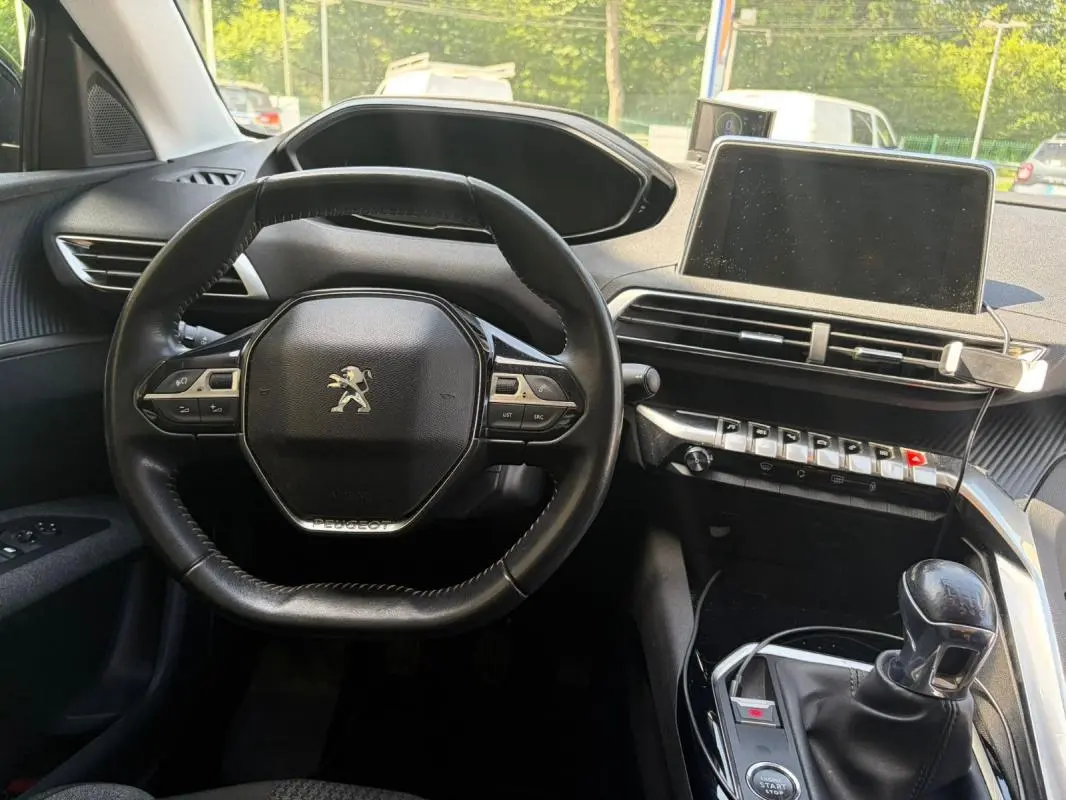 Intérieur du Peugeot 3008 2021 noir, vue centrée sur le volant, tableau de bord et levier de vitesses manuel.