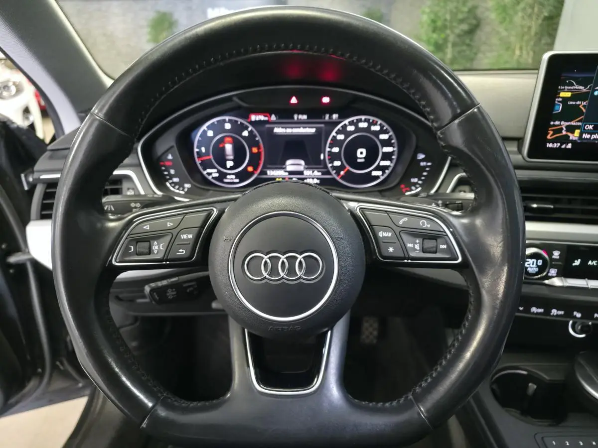 Vue rapprochée du volant en cuir noir d'une Audi A4 Allroad 2017 avec tableau de bord numérique et écran de navigation.
