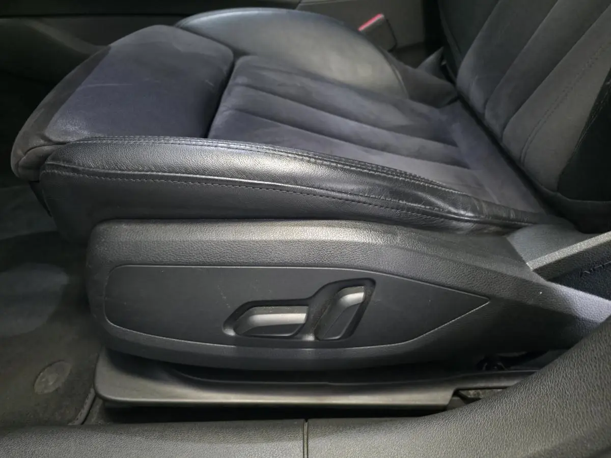 Gros plan sur le siège avant conducteur en cuir et Alcantara noir avec commandes électriques latérales dans l'Audi A4 Allroad gris.