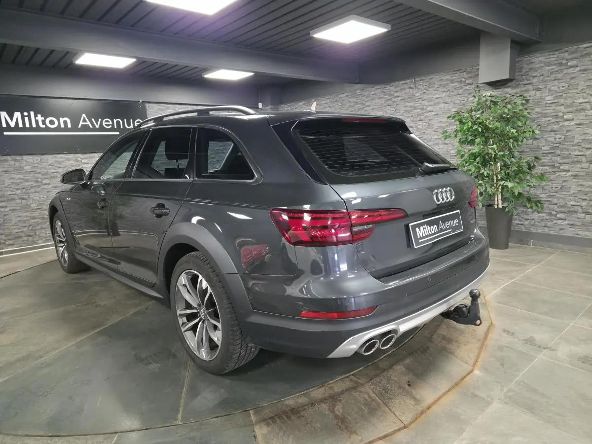 Audi A4 Allroad gris métallisé vue 3/4 arrière droit avec jantes 18 pouces et crochet d'attelage en intérieur showroom.