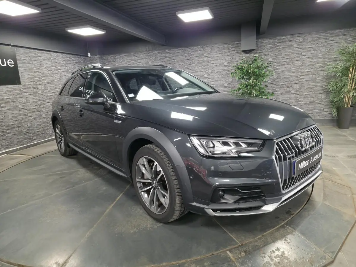 Audi A4 Allroad gris métallisé vue 3/4 avant droit en intérieur avec calandre chromée et jantes 5 branches doubles.
