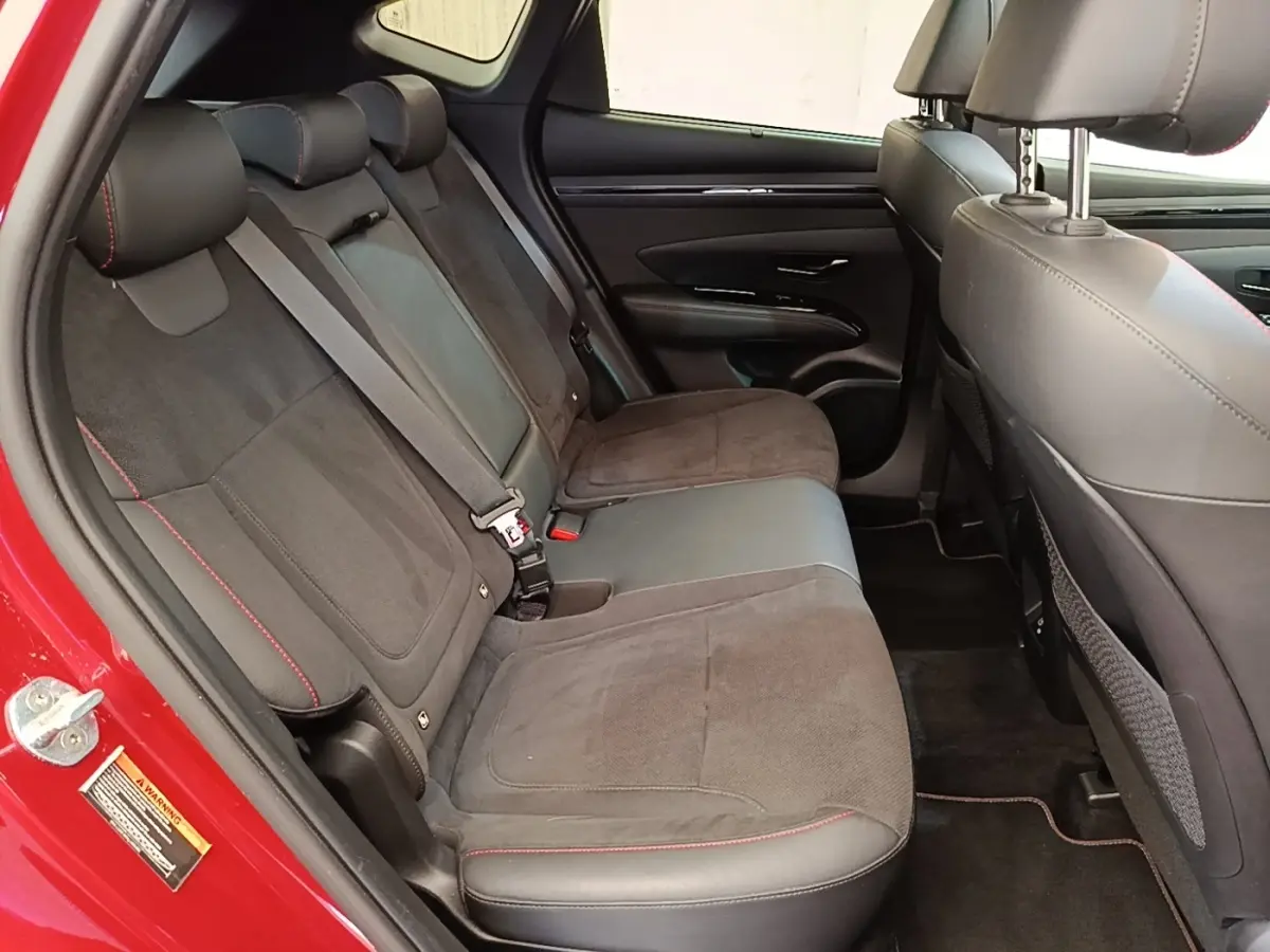 Vue intérieure côté gauche des sièges arrière en tissu et cuir noir avec surpiqûres rouges d’un Hyundai Tucson rouge.