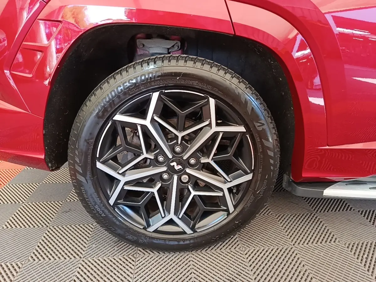 Gros plan sur la roue arrière droite rouge d’un Hyundai Tucson 1.6 CRDI N Line avec jante alliage noire et argentée.