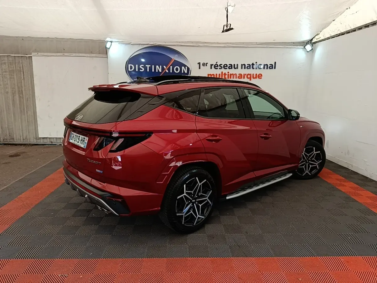 Hyundai Tucson rouge 2022 en 3/4 arrière droit, avec jantes noires et toit noir contrasté.