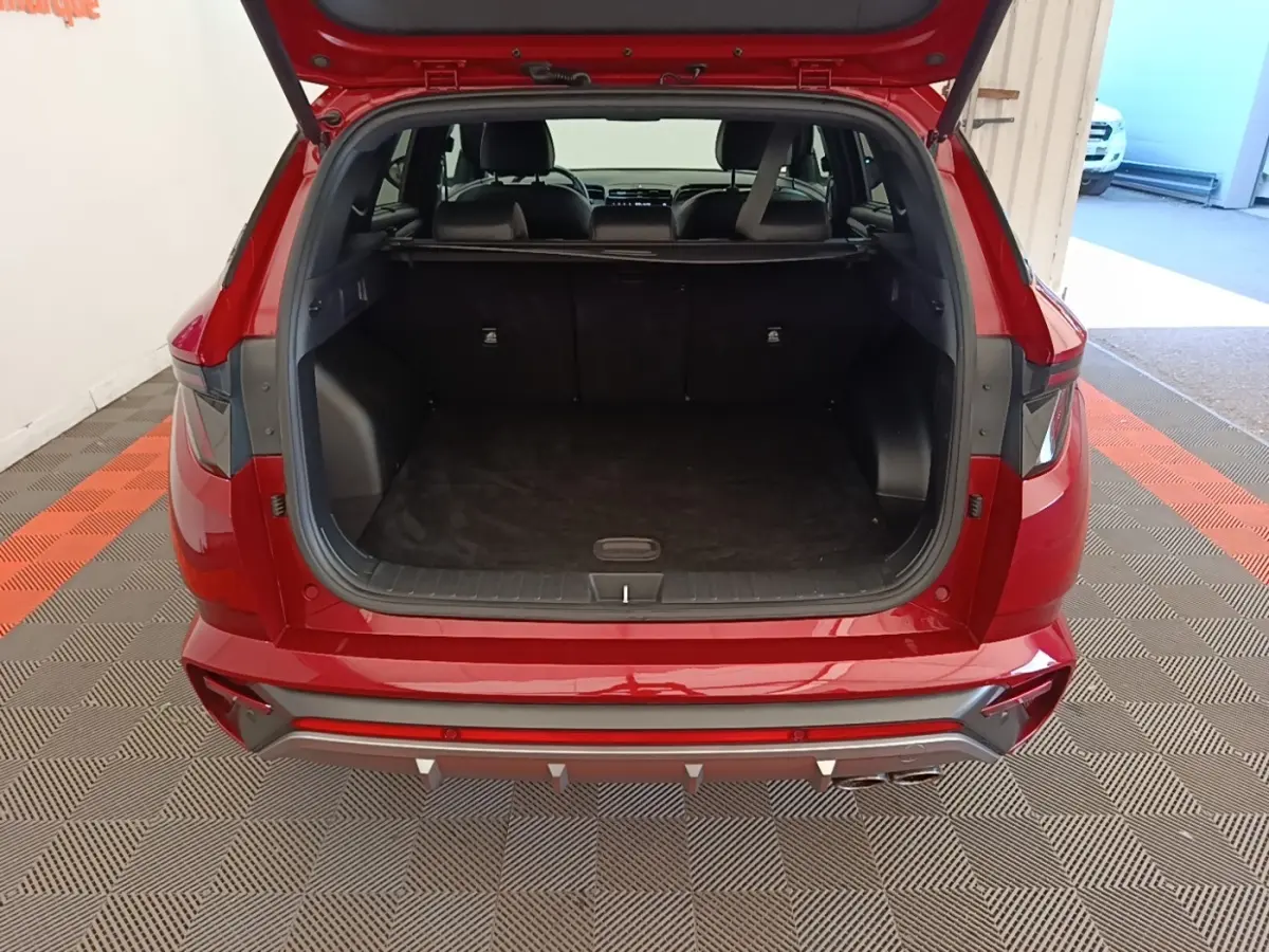 Vue arrière ouverte du coffre d'un Hyundai Tucson rouge 2022, montrant l'espace de chargement et l'intérieur sombre.