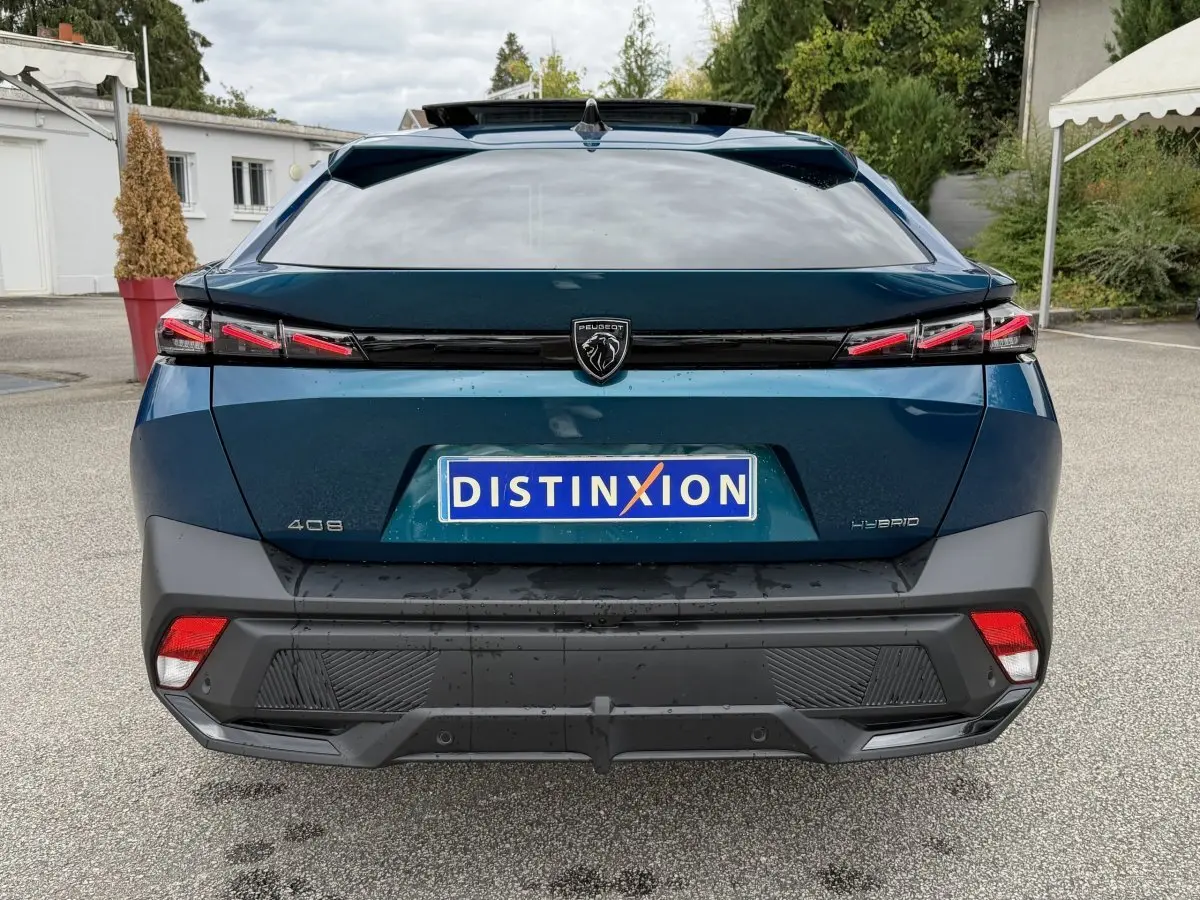 Vue arrière d'une Peugeot 408 PHEV 225 GT bleu 2023 avec feux LED et logo lion central sur parking.