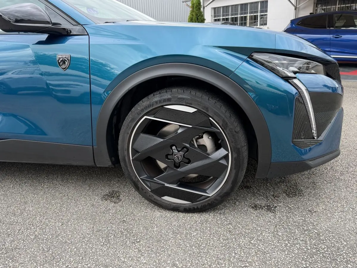 Gros plan sur la roue avant droite et l’aile avant bleu métallisé du Peugeot 408 PHEV 225 GT 2023.