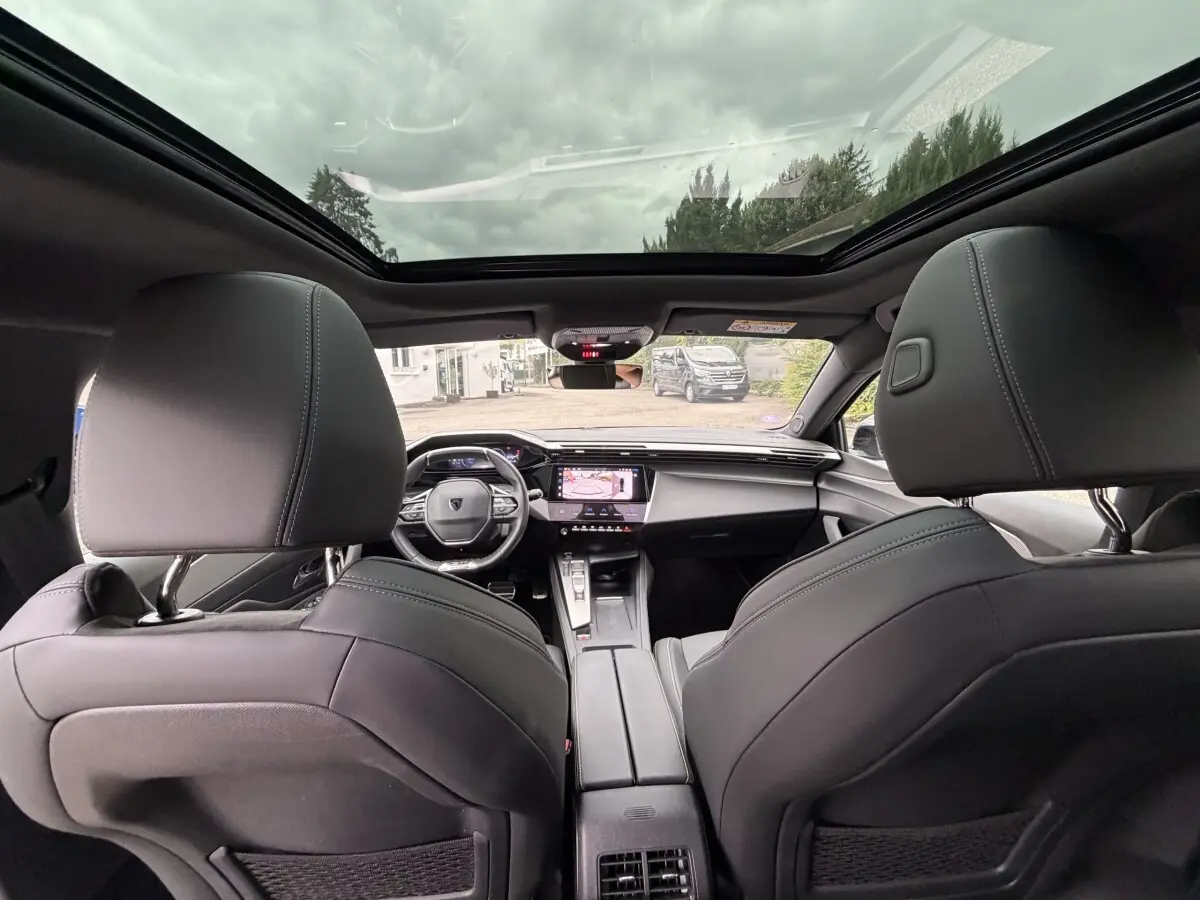 Vue intérieure arrière du Peugeot 408 PHEV 225 GT 2023, sièges noirs et toit panoramique vitré.