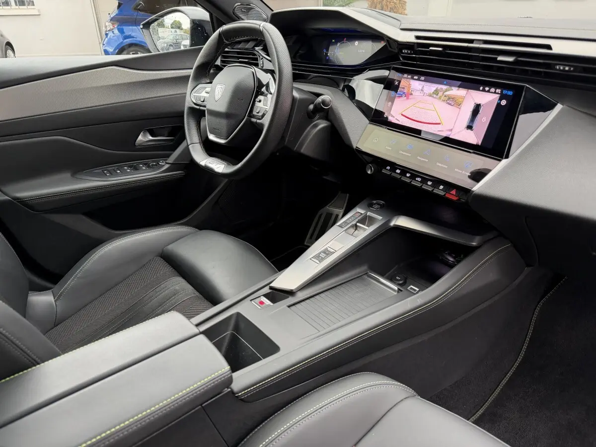 Intérieur noir de la Peugeot 408 PHEV 225 GT vu côté conducteur, avec écran tactile affichant la caméra de recul.