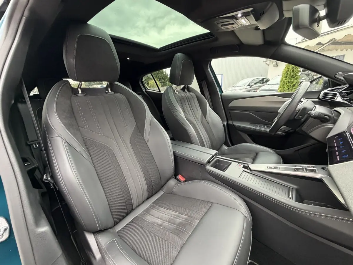 Vue intérieure avant droite du Peugeot 408 PHEV 225 GT 2023 bleu, sièges cuir et alcantara noirs avec toit panoramique.