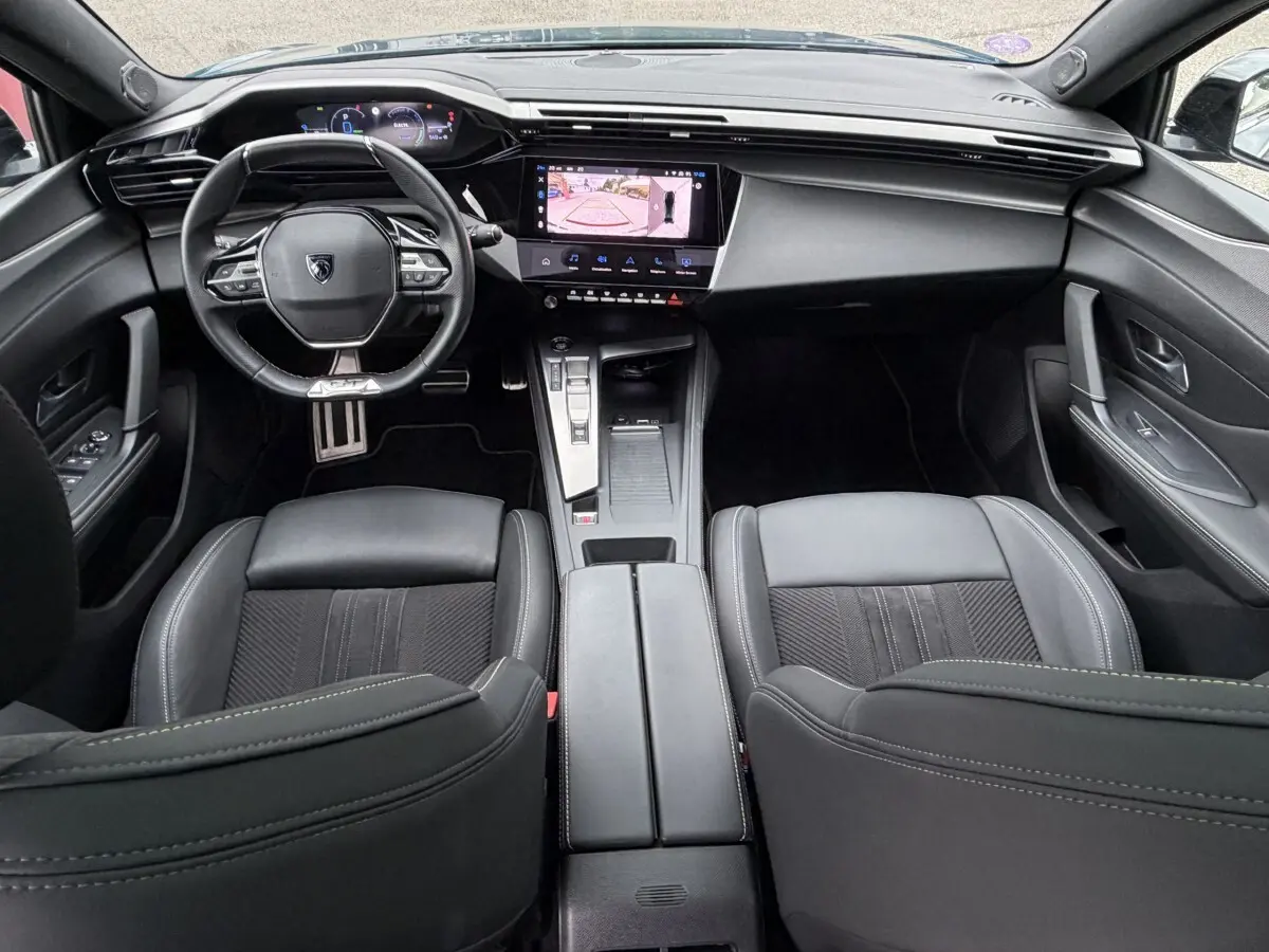 Vue intérieure avant du Peugeot 408 PHEV 225 GT 2023, tableau de bord noir avec écran tactile affichant caméra de recul.