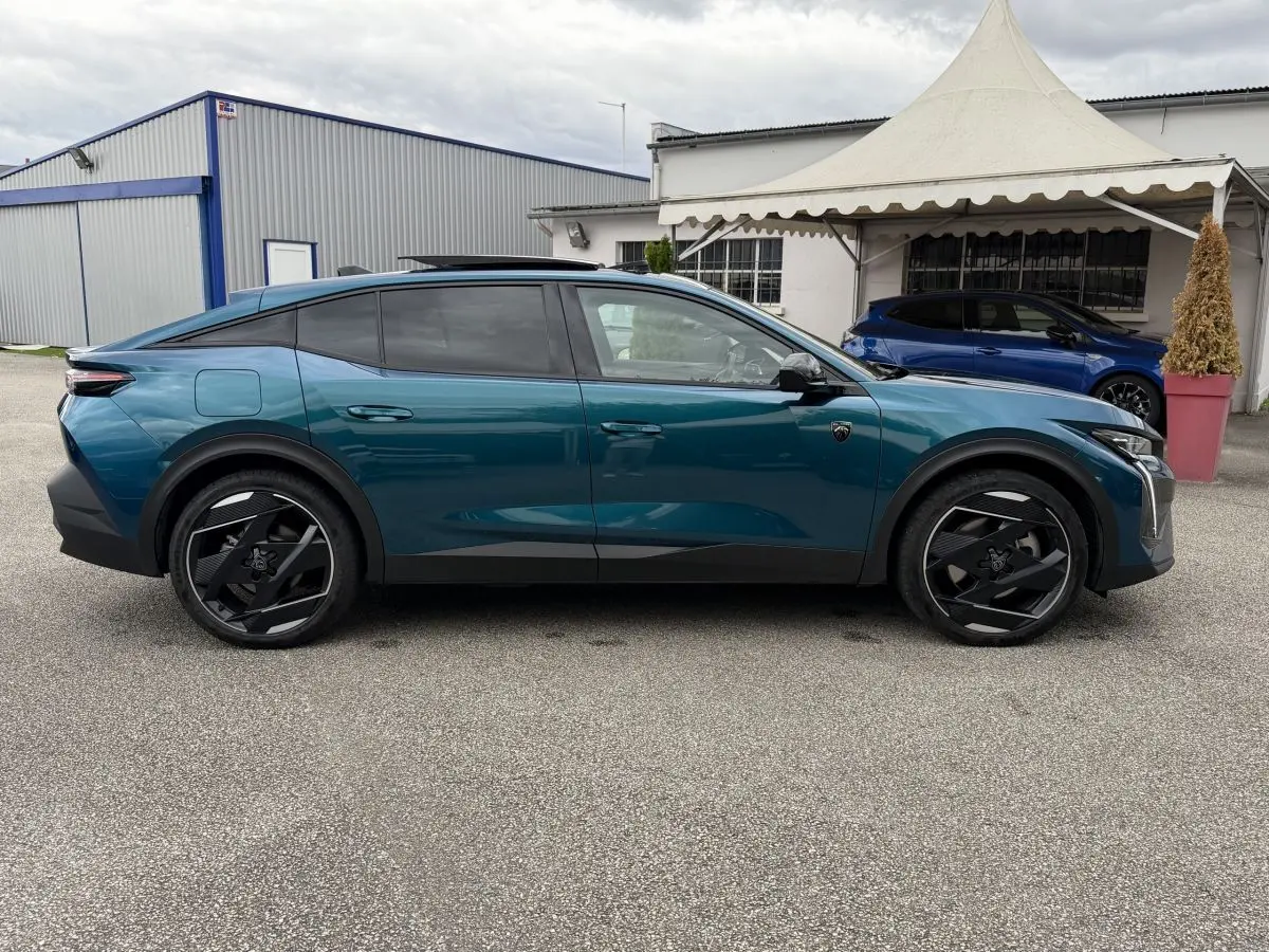 Vue de profil côté gauche d’une Peugeot 408 PHEV 225 GT bleu avec jantes noires au design futuriste.