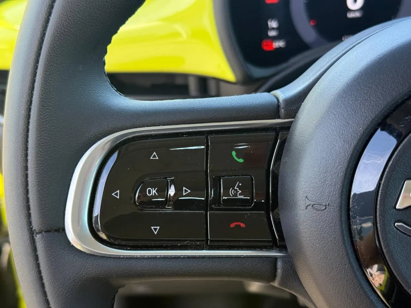 Gros plan sur les commandes multifonctions à gauche du volant d'une FIAT 500 électrique jaune Amalfi 2024.
