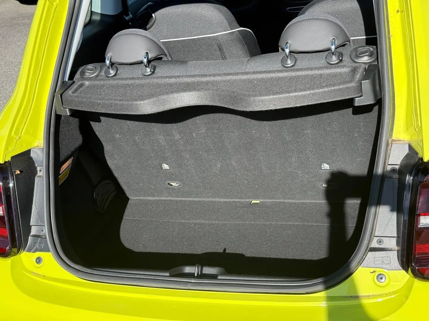 Coffre ouvert vu de l'arrière d'une FIAT 500 électrique jaune Amalfi, banquette arrière rabattable visible.