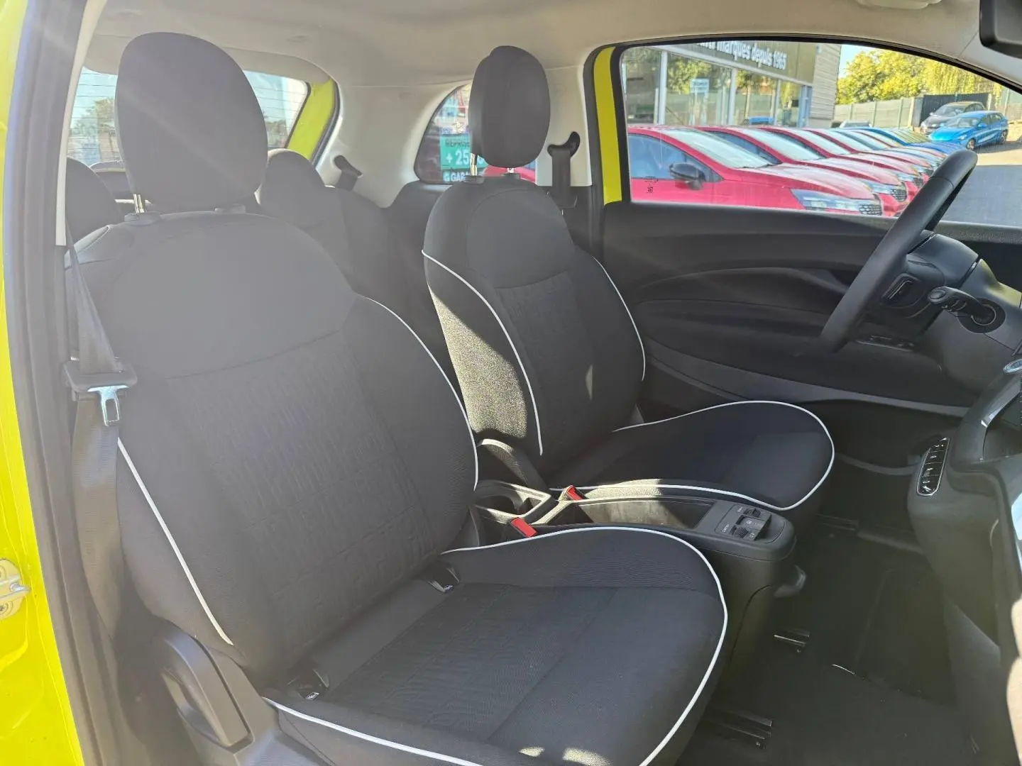 Vue intérieure côté gauche montrant les sièges noirs avec surpiqûres blanches d'une FIAT 500 électrique jaune 2024.
