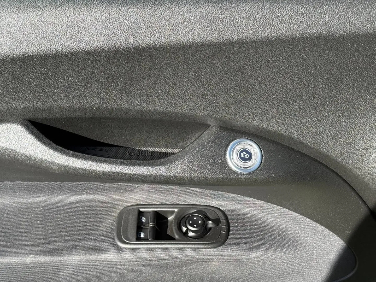 Détail de la commande de verrouillage et des réglages des rétroviseurs sur la porte côté conducteur d'une FIAT 500 e jaune.