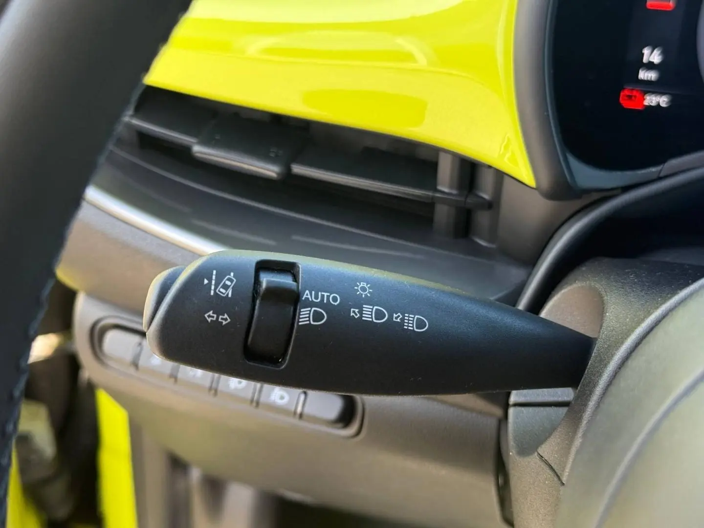 Gros plan sur la commande des feux avec tableau de bord jaune vif de la Fiat 500 électrique 2024.