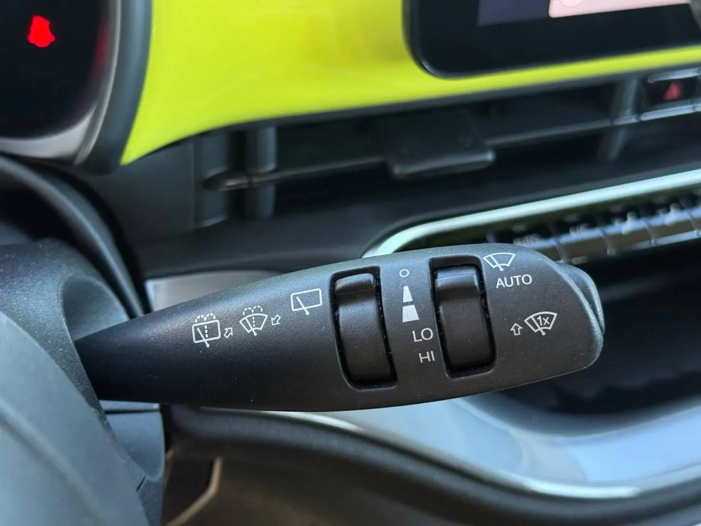 Gros plan sur la commande des essuie-glaces dans l’habitacle jaune vif de la Fiat 500 électrique MY24.