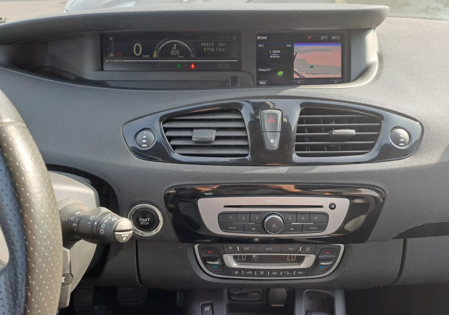 Tableau de bord intérieur du Renault Scenic III 2016, avec écran central, commandes climatisation et volant partiel visible.