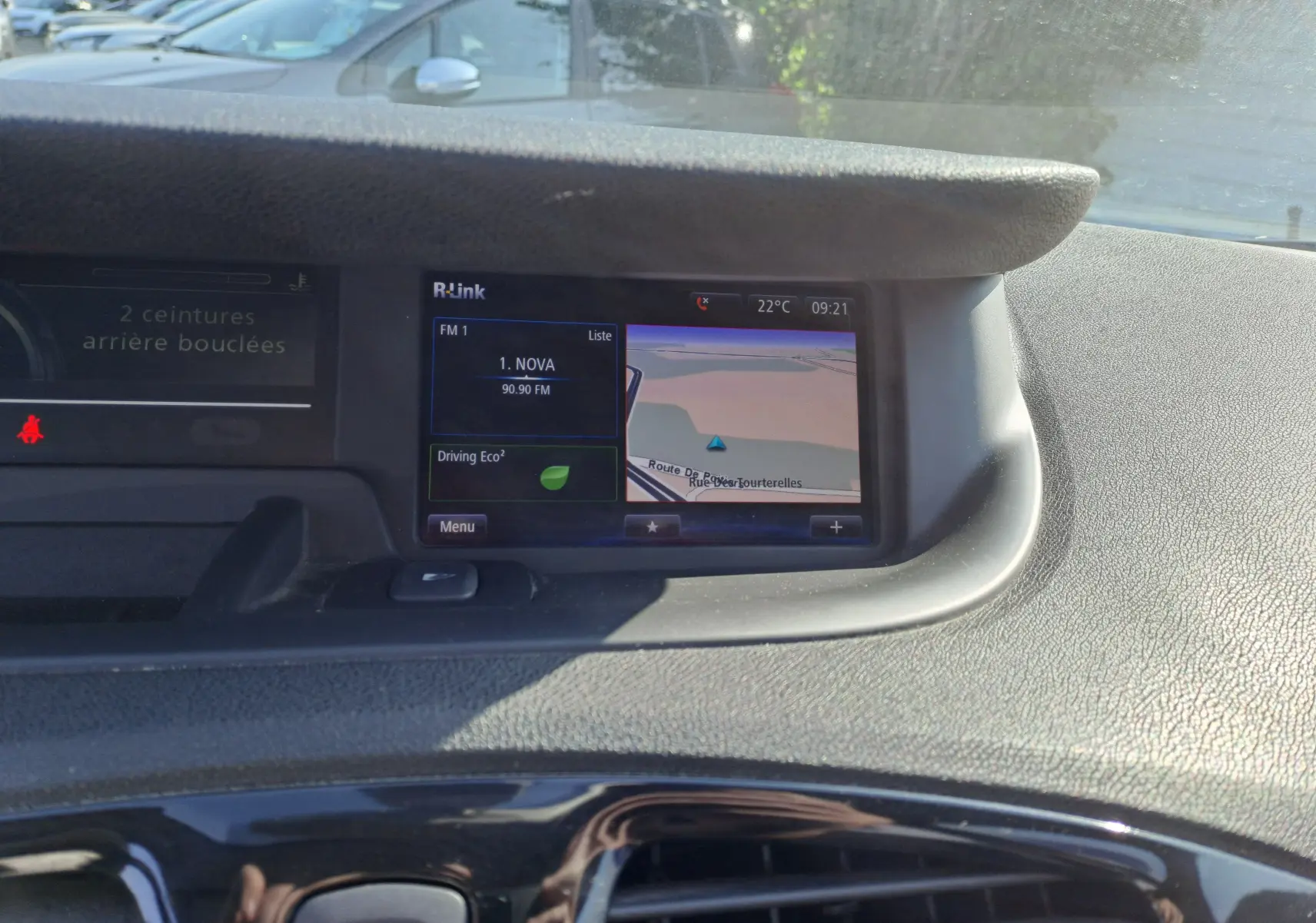 Vue rapprochée de l'écran central du tableau de bord du Renault Scenic III gris, affichant la navigation et la radio FM.